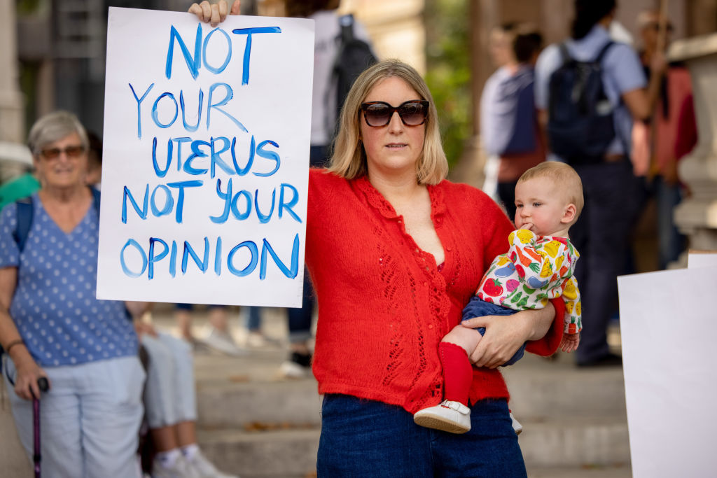 A pro-abortion protester holds a placard and her baby during...