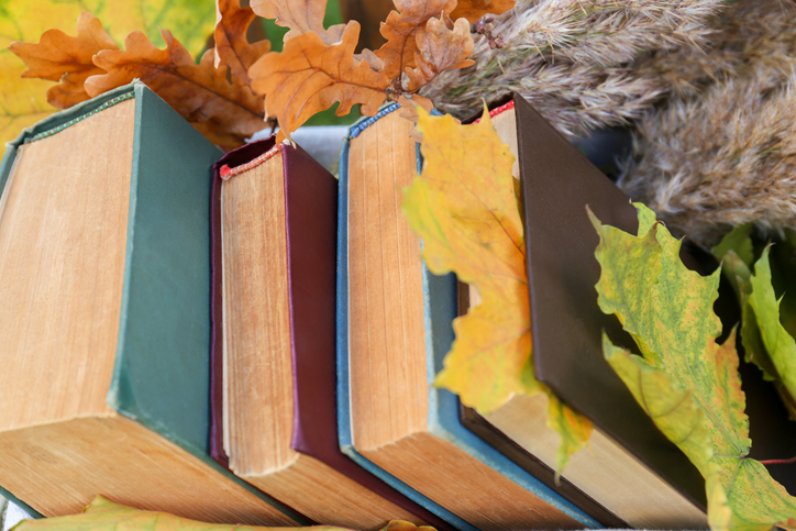 Different books and maple leaves, closeup. Autumn atmosphere