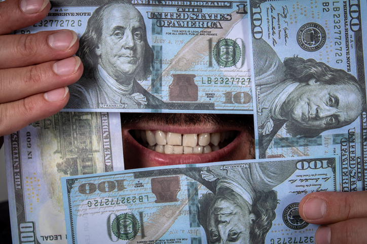 Smile of a person surrounded by hundred dollar bills
