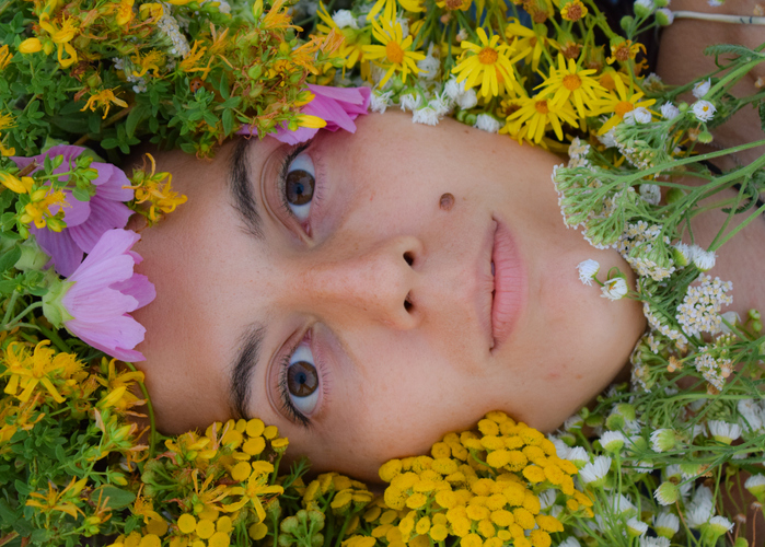 Female face adorned by a vibrant array of wildflowers and herbs